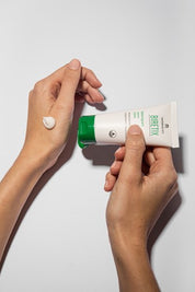a close-up of a woman's hands squeezing out BIRETIX Isorepair Cream from its tube for skincare application
