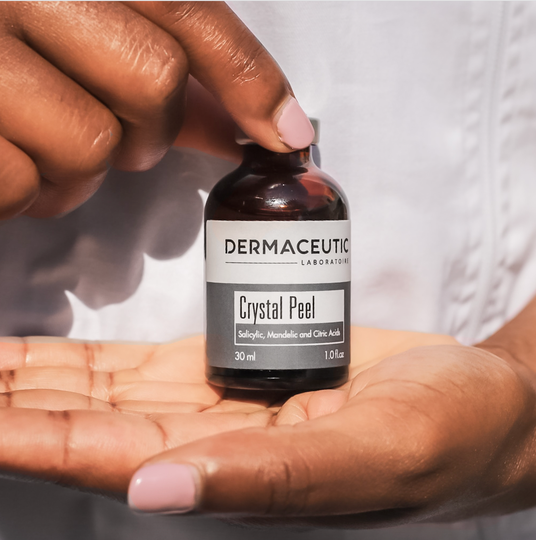 colored hands holding a bottle of A bottle of Dermaceutic Laboratoire Crystal Peel 30ml